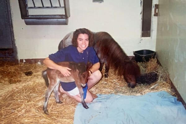veterinary student holding small foal with leg wrapped, photo