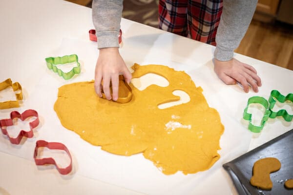 Holiday dog treats dough rolled out and hand pressing cookie cutter into it, photo