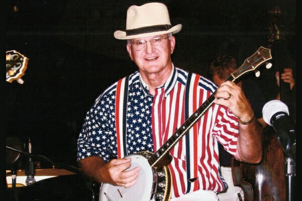 Dr. Buzby's father playing the banjo and wearing a stars and stripes shirt, photo