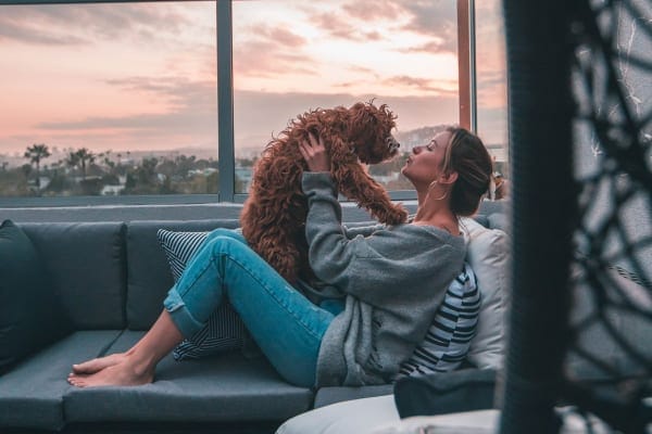 Dog mom holding up her pet and giving kisses, sitting on a balcony, photo