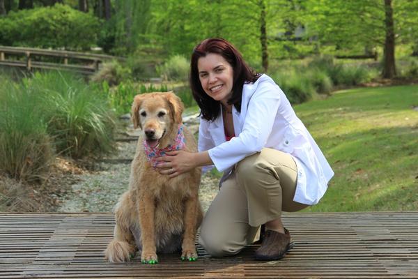 Dr. Buzby wearing white a veterinary jacket sitting beside a senior Golden Retriever wearing ToeGrips for dogs