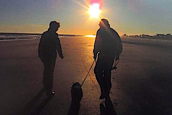 silhouette of couple walking on beach with dog, photo 