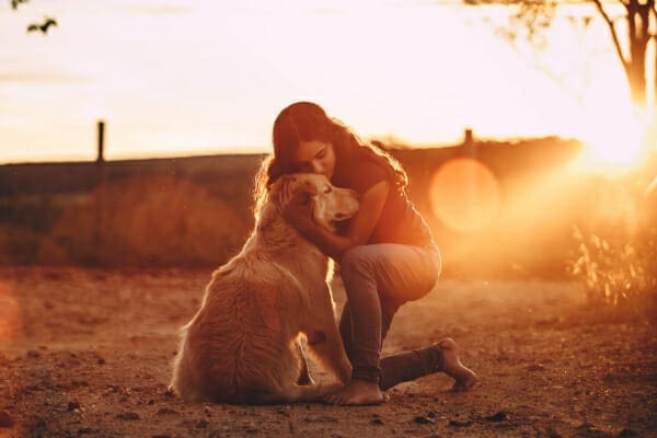 Women hugging her Golden Retriever at sunset, photo