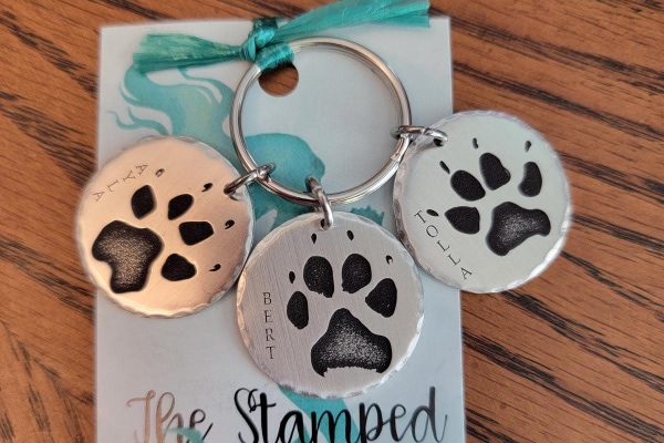 Personalized memorial jewelry including key chains with names of passed pets with paw prints on them