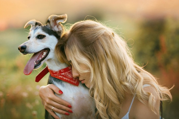 Blonde woman hugging her mixed breed dog