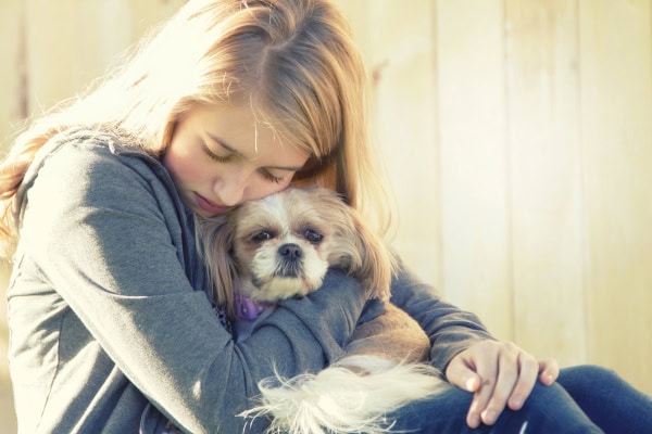 Girl hugging her dog in her lap