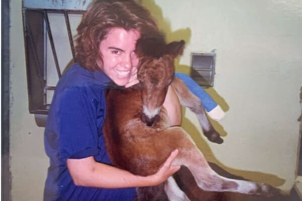 Vet student, Dr. Buzby, cradling a young foal, photo