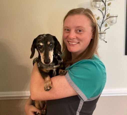 Veterinarian Rebekah Fikes smiling and cuddling her senior dog in her arms