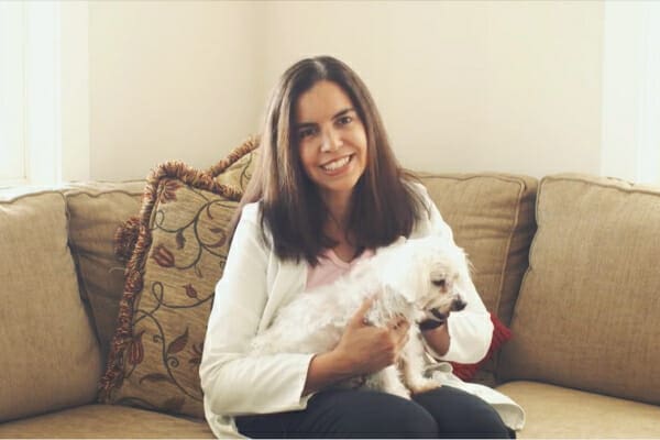 Dr. Julie Buzby on a couch holding a Bichon mix, photo